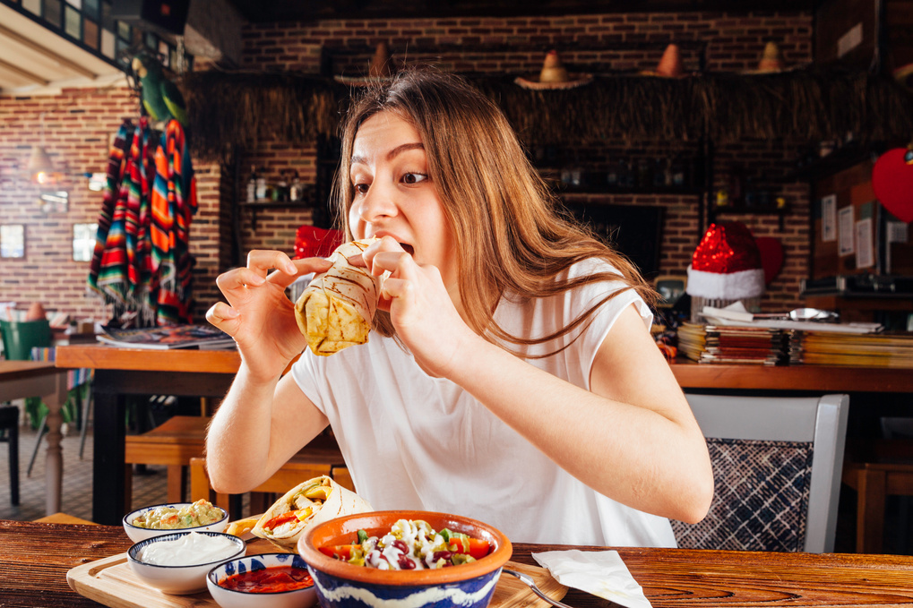 Young woman eating burrito for lunch